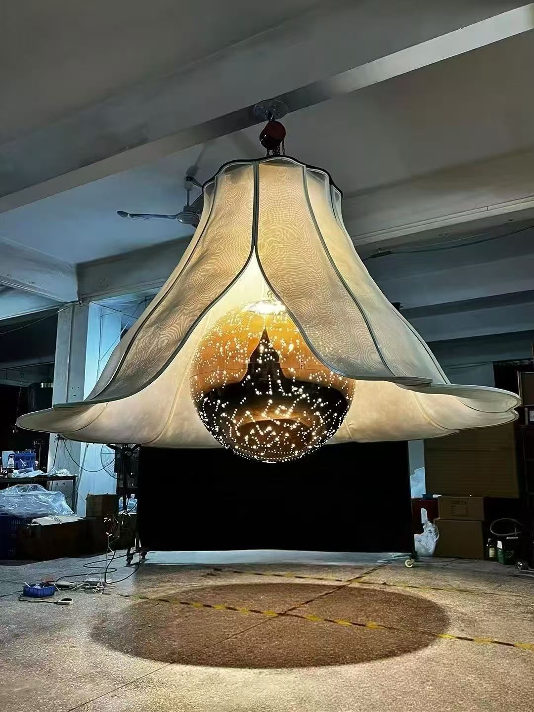 Flared chandelier with illuminated central sphere during workshop testing