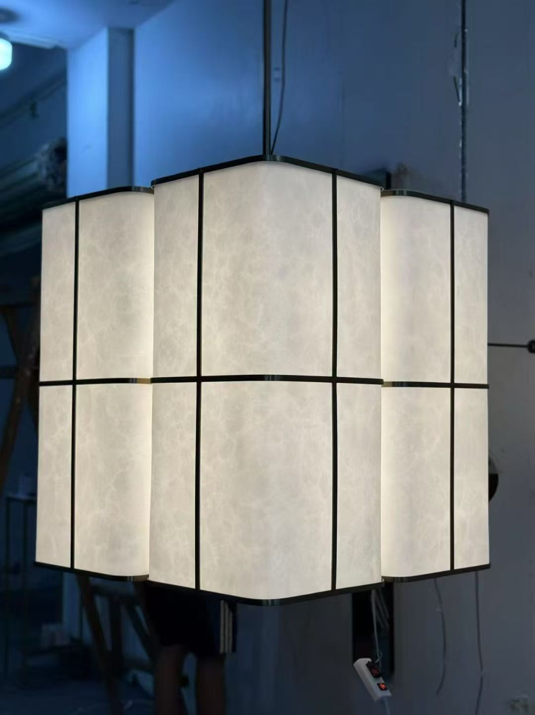 Three-panel illuminated pendant photographed in the workshop