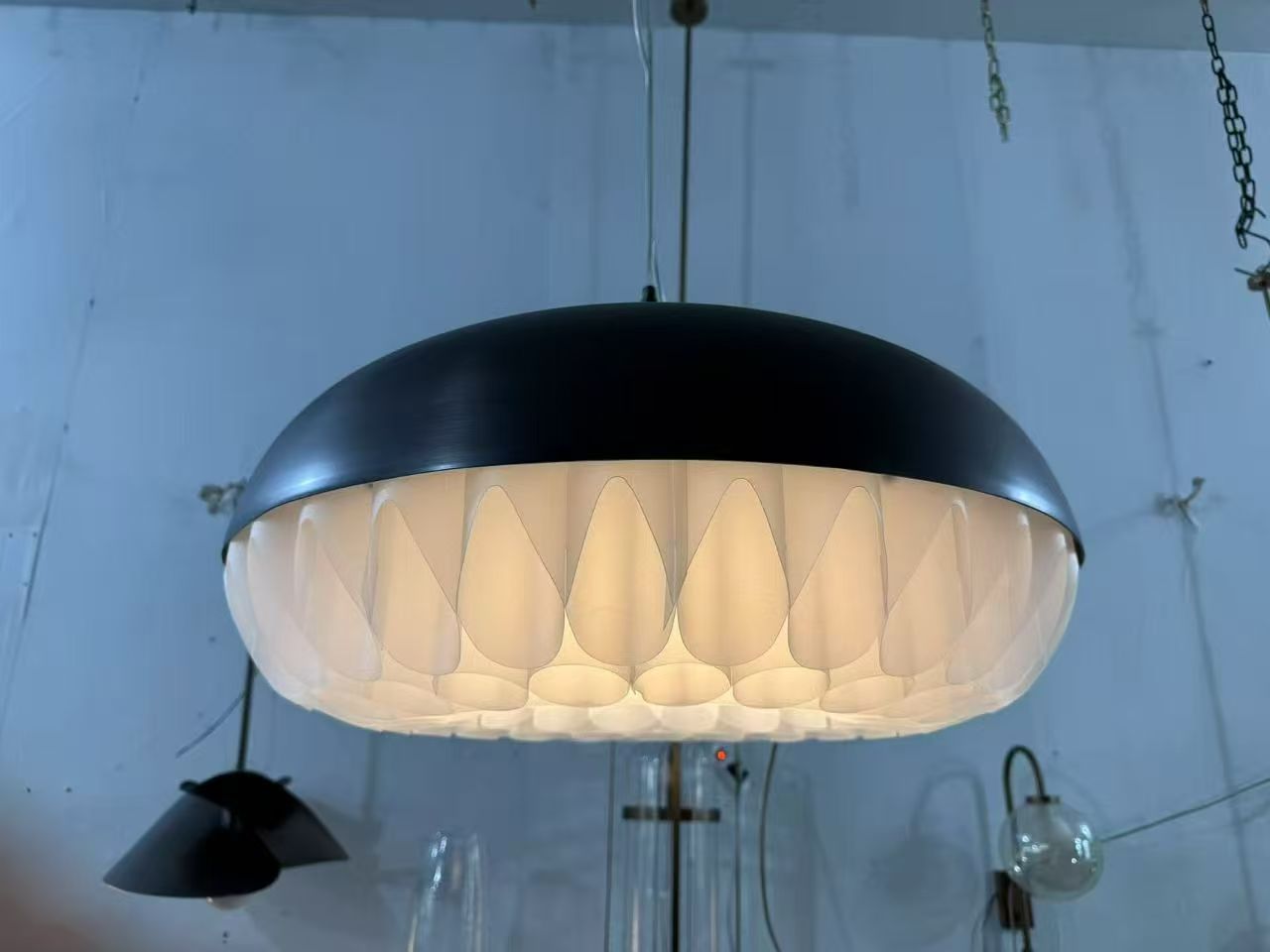 Dark dome pendant with illuminated lower shade in the workshop