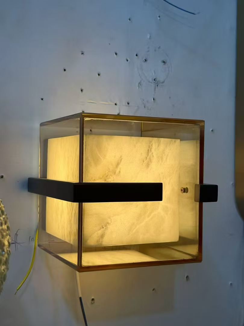 Glass-box wall light with glowing inner panel photographed in the workshop