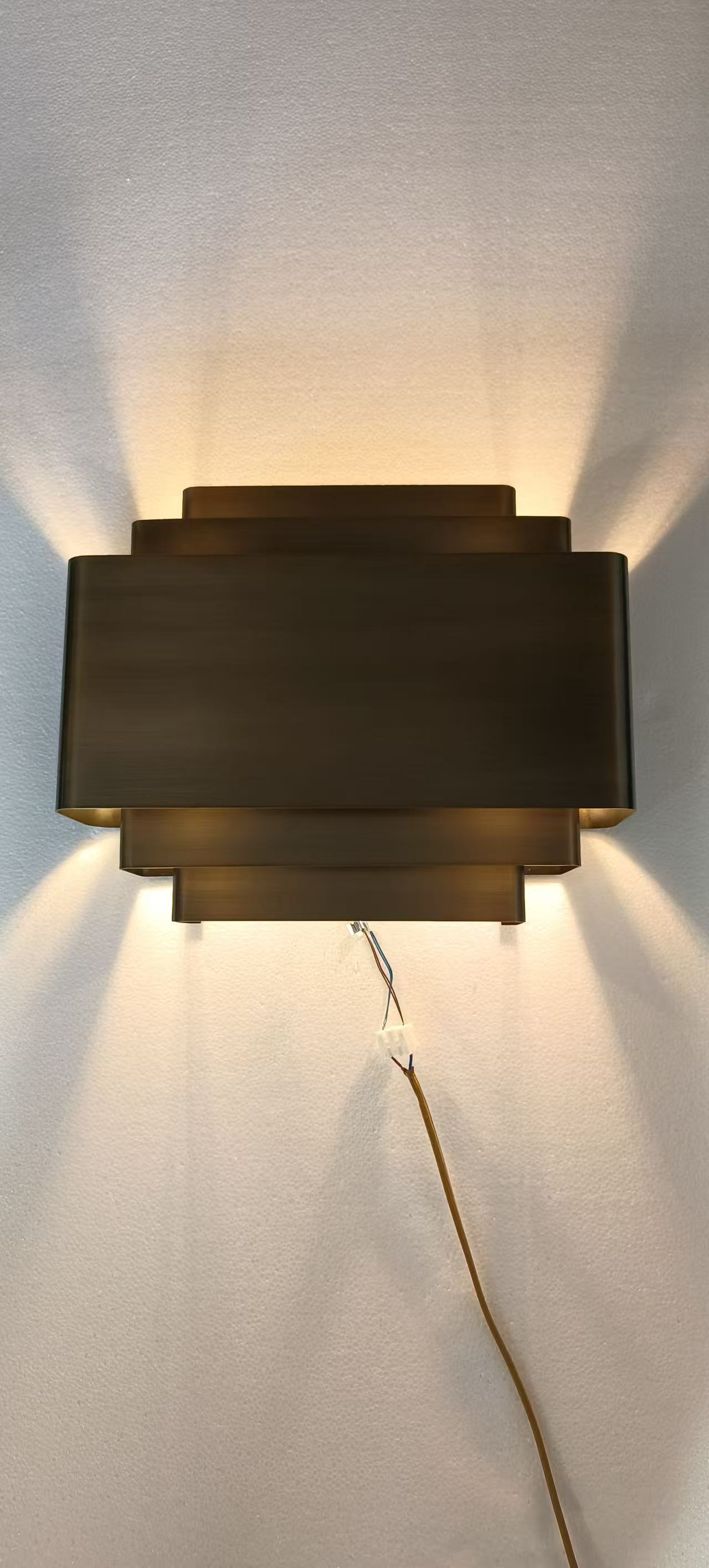 Layered brass wall light photographed in the workshop