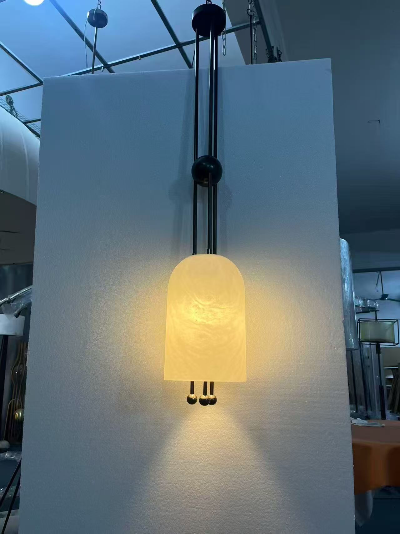 Single translucent suspended form with an elongated dark metal structure in the workshop