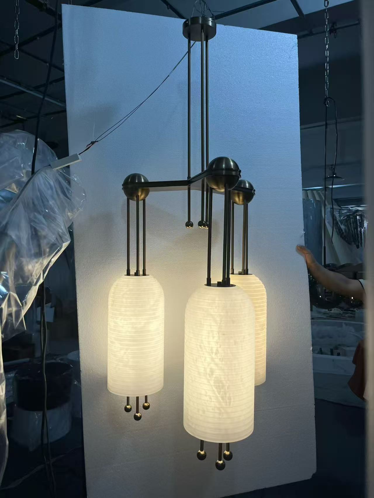 Three translucent lighting forms arranged within a dark metal framework in the workshop