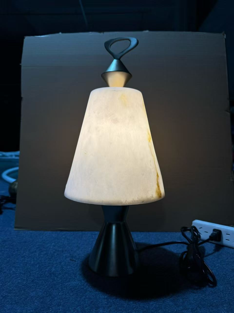Table light with a textured translucent shade, loop finial and dark tapered base in the workshop