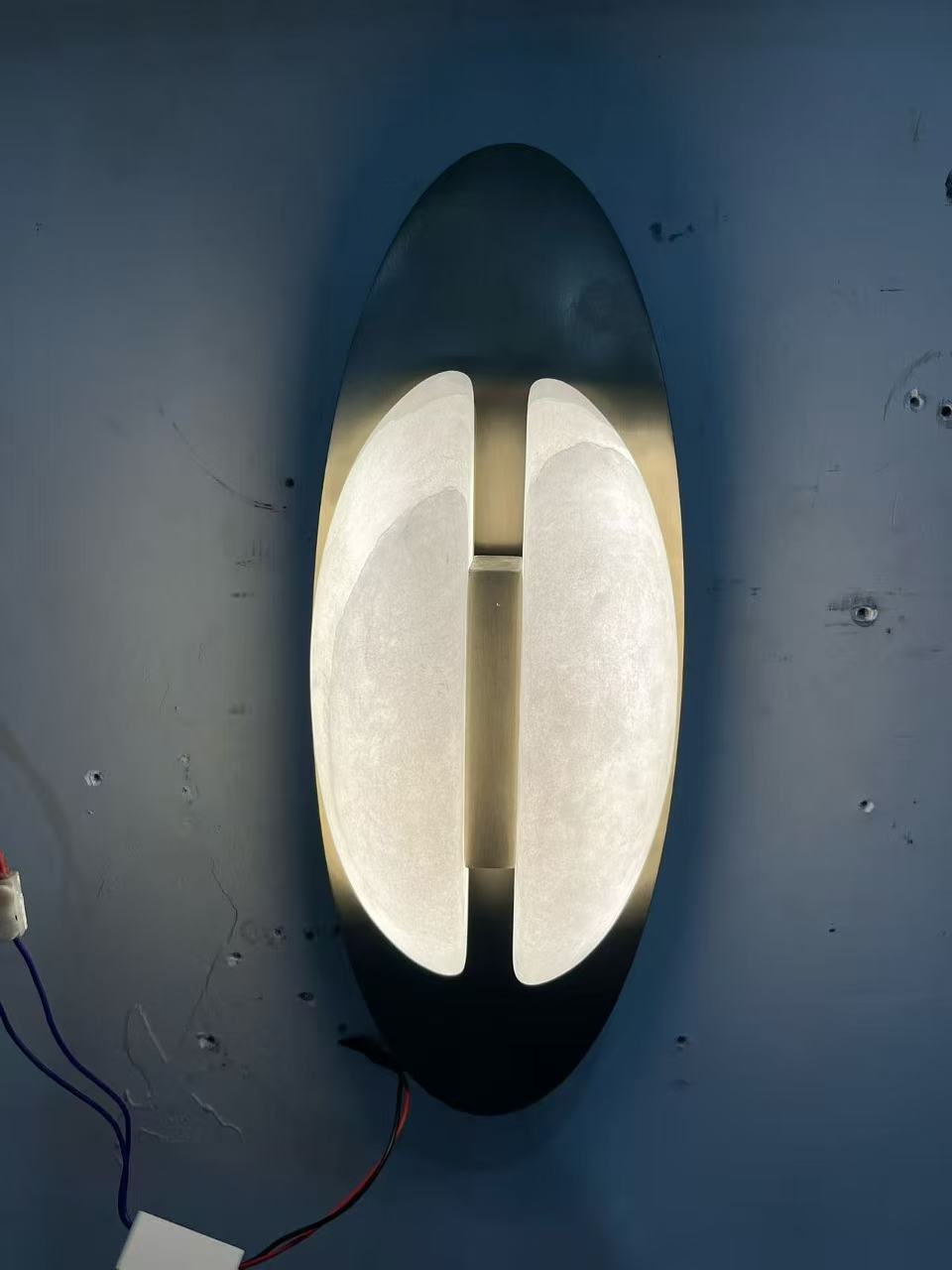 Two softly illuminated elements framed by a vertical oval backplate in the workshop