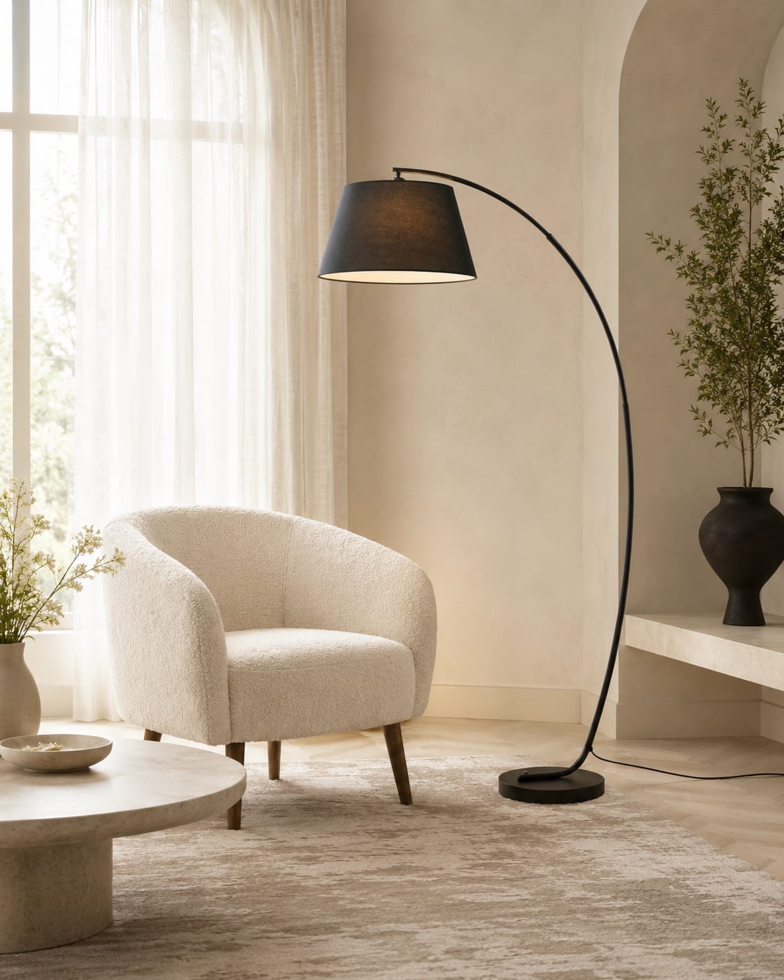 Custom arc reading floor lamp with a curved black metal structure and dark fabric shade beside a lounge chair
