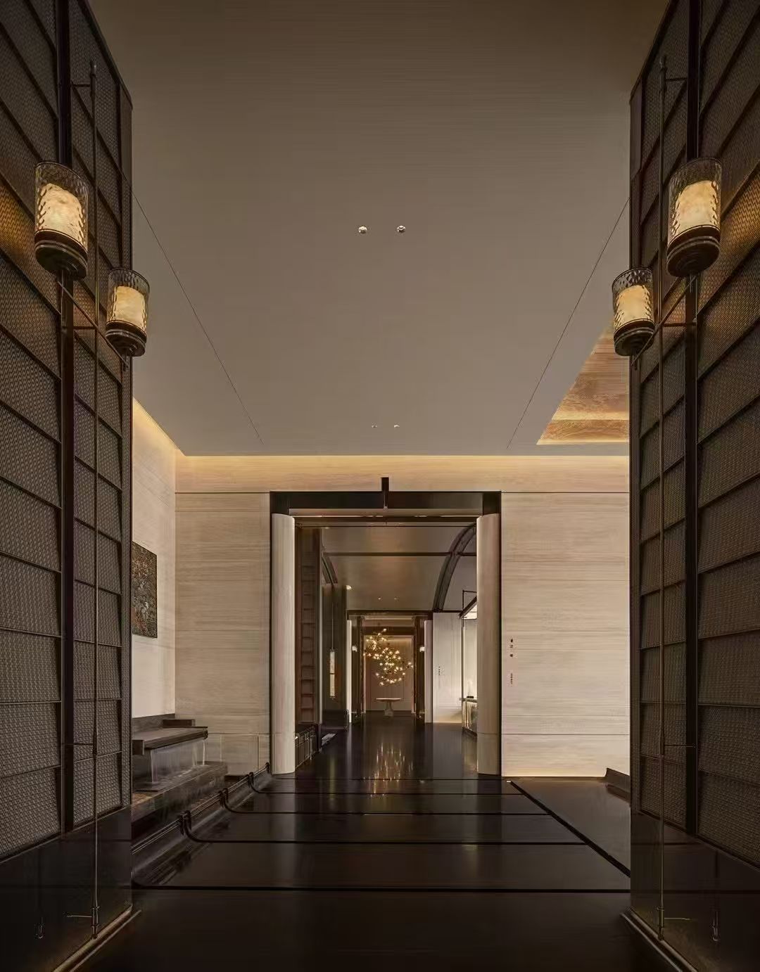 Repeated glowing wall lights along a tall interior passage
