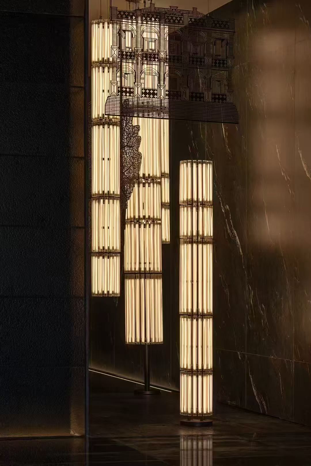 Tall cylindrical illuminated forms beside dark architectural panels