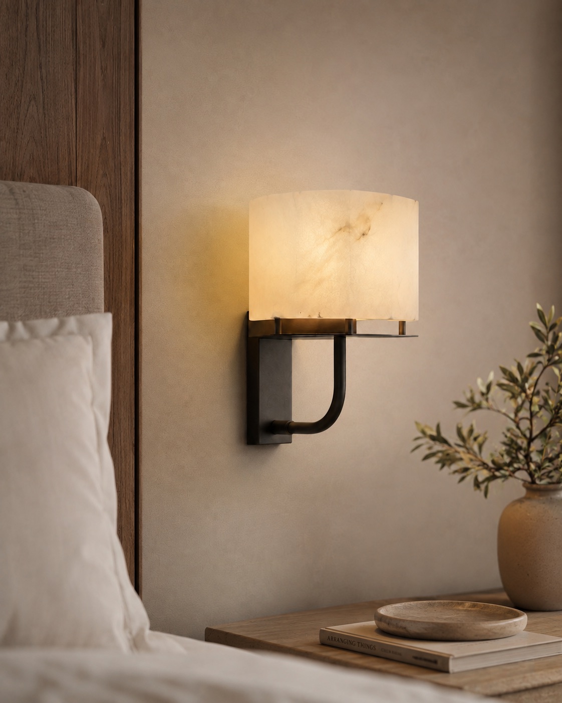 Compact custom alabaster bedside wall light with a dark bronze bracket beside a hotel bed